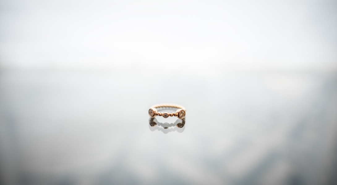 a golden ring with stones on the blurred white surface