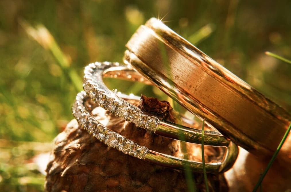 tree golden rings with stones, one is plain on the background of green blurred grass