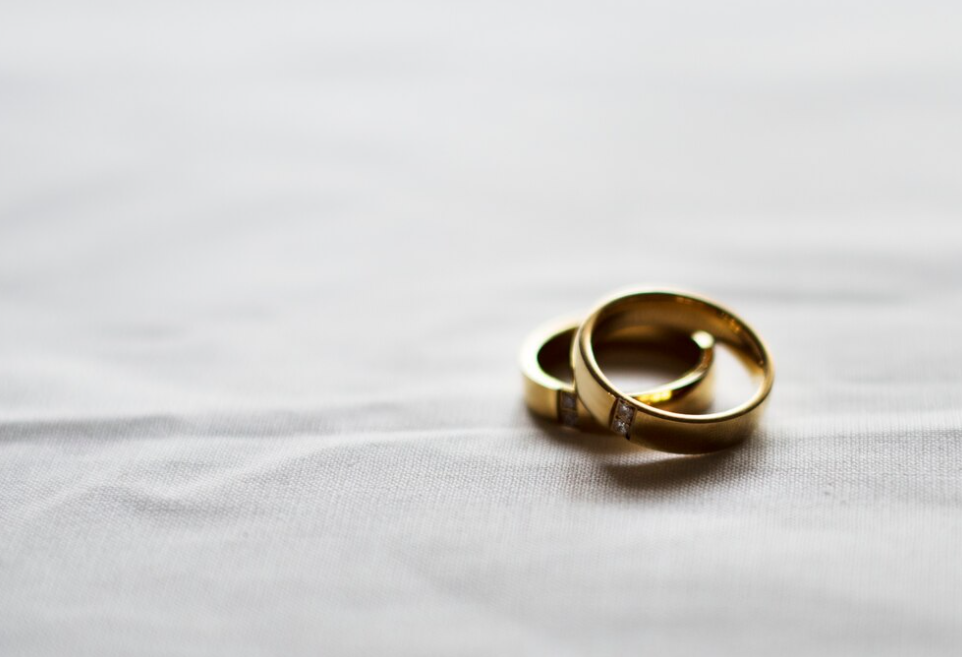 Simple gold wedding bands on a plain grey fabric background