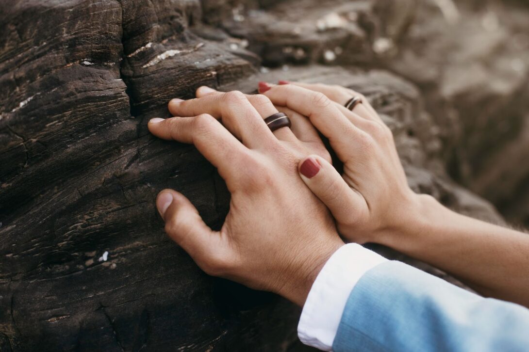 Newlyweds holding hands with black wedding rings on it